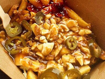 A box of poutine topped with jalapeños